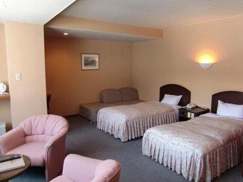a hotel room with two beds and a chair at Hakuba Hotel Ougiya in Hakuba