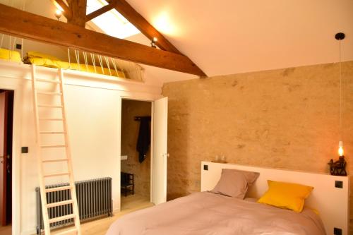 Un dormitorio con una cama con almohadas amarillas y una escalera en Les Maillettes en Les Épesses
