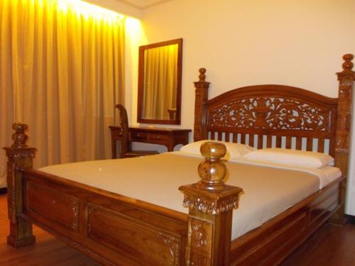 uma cama de madeira num quarto com um espelho e cortinas em Bali Style Apartment @ Imperial Court em Cameron Highlands