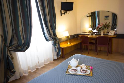 Cette chambre comprend une table avec un plateau de beignets et un miroir. dans l'établissement Albert Hotel, à Milan