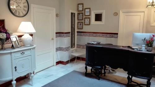a room with a desk with a computer and a clock at Le Petit París in Seville