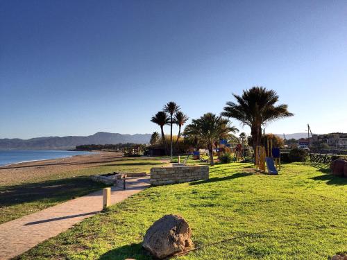 a park with palm trees and a sandy beach at Maria's Place in Polis Chrysochous