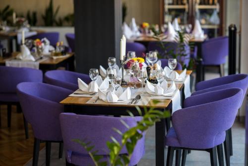 a dining room with purple chairs and a table with wine glasses at Hotel Emporium in Bihać