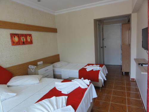 a hotel room with two beds with red and white sheets at Altinersan Hotel in Didim