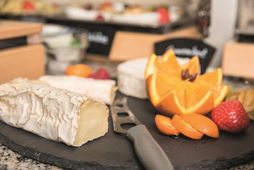 a cutting board with cheese and fruit on a counter at Arcus Hotel München Messe in Feldkirchen