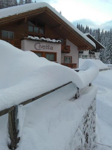 a house covered in snow on a roof at Hotel Garni Civetta in Selva di Cadore