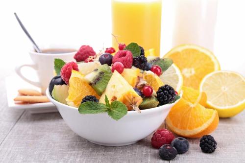 a white bowl of fruit salad with berries and oranges at Hotel Garni Civetta in Selva di Cadore