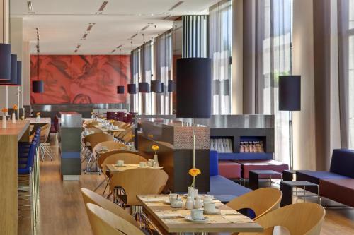 a restaurant with tables and chairs and a red painting at IntercityHotel Leipzig in Leipzig