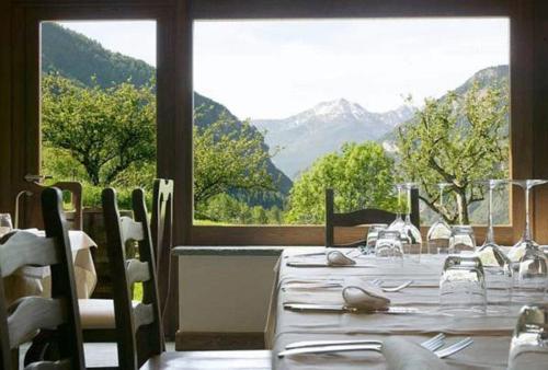 a dining room with white tables and chairs and a large window at Maison Tissiere in Antey-Saint-André