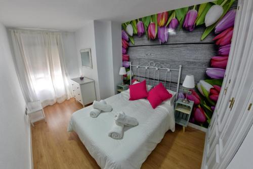 マラガにあるApartamento Boqueronのベッドルーム1室(ピンクの枕と花の壁付)