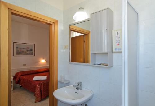 a bathroom with a sink and a mirror and a bed at Hotel Regina in Lido di Camaiore