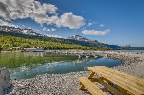 a wooden bench sitting on a beach next to a river at Garsnes Brygge in Sjøvegan