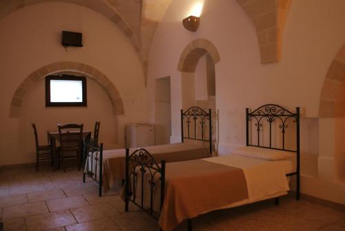 a bedroom with two beds and a table in a room at Masseria Nuova in Francavilla Fontana