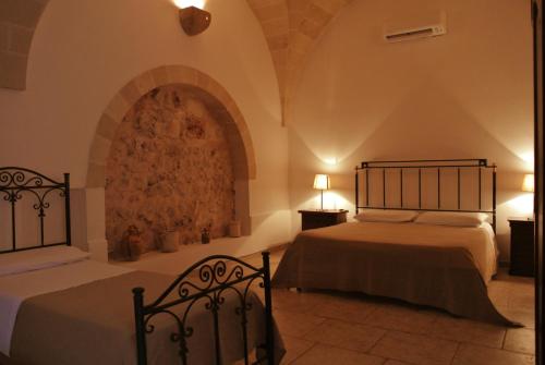 a bedroom with two beds and a stone wall at Masseria Nuova in Francavilla Fontana