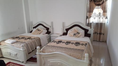 2 Betten in einem weißen Zimmer mit Röcken in der Unterkunft Winta Hotel in Hārer