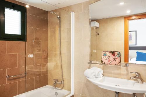 a bathroom with a shower and a sink and a mirror at Hotel Pocillos Playa, solo Adultos in Puerto del Carmen