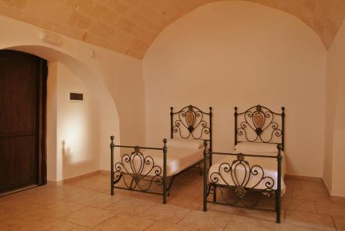 two beds in a room with an archway at Masseria Nuova in Francavilla Fontana