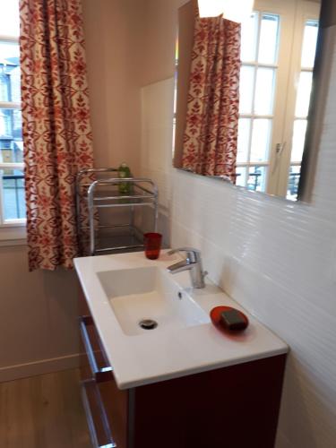 une salle de bain avec un lavabo, un miroir et une fenêtre dans l'établissement Appartement cosy dans le centre de Honfleur, à Honfleur
