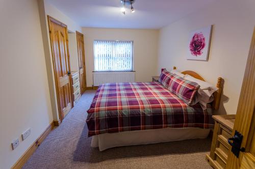 1 dormitorio con 1 cama con manta a cuadros en fairhill holiday let, en Ballycastle