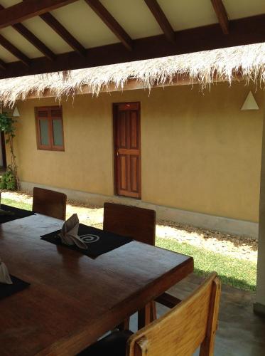 a dining room table with chairs and a thatch roof at WildEscape, Yala Blocks 3 & 5 in Buttala