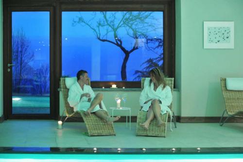a man and woman sitting in chairs in front of a pool at Maison Tissiere in Antey-Saint-André