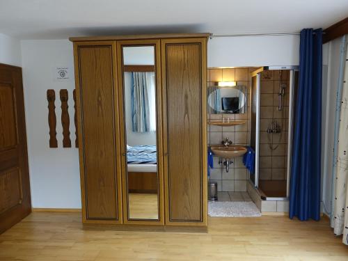Habitación con armario de madera y lavamanos. en Gästehaus Margareta en Wald im Pinzgau
