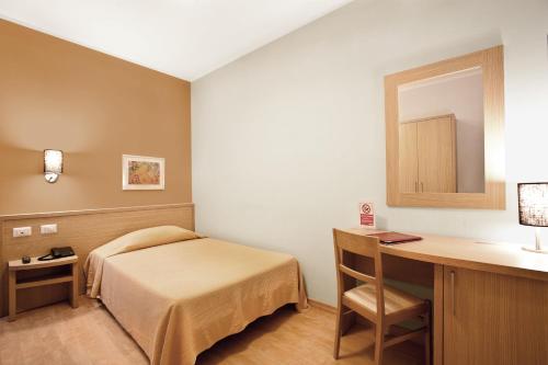 a bedroom with a bed and a desk with a mirror at Hotel La Campagnola in Fucecchio