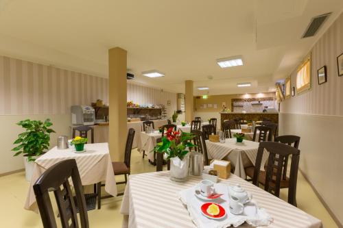 um restaurante com mesas brancas e cadeiras com flores em Hotel La Campagnola em Fucecchio