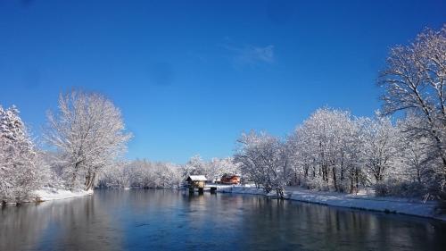 a river with snow covered trees and a bridge at Vacation Home Pliva in Šipovo