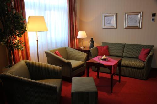 a living room with couches and a table and a lamp at Hotel Amaris Bremerhaven in Bremerhaven