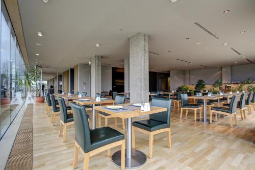 a restaurant with wooden tables and blue chairs at Centro Park Hotel Stuttgart, Trademark Collection by Wyndham in Ostfildern