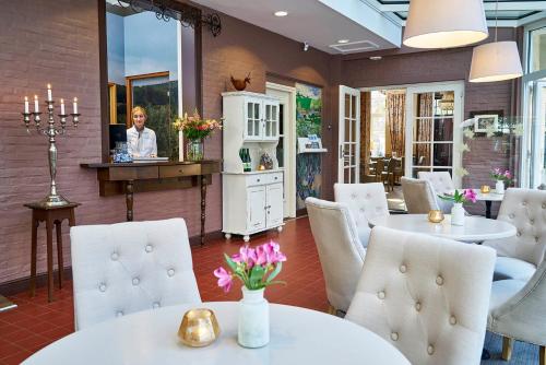 Hotel Brull في ميشيلين: مطعم بطاولات بيضاء وكراسي وامرأة في مرآة