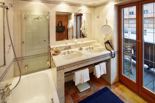 a bathroom with two sinks and a tub and a shower at Post Lech Arlberg in Lech am Arlberg