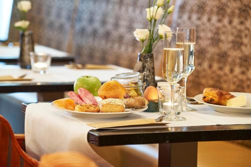 a table with plates of food and glasses of wine at Saillant Hotel Maastricht City Centre - Auping Hotel Partner in Maastricht