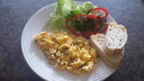 ein Teller mit Essen mit Eiern und Brot und einem Salat in der Unterkunft Berg Toboz Panzió in Pécs