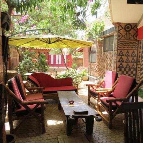 a patio with chairs and a table and an umbrella at Maison d'hôtes Chez Giuliana in Ouagadougou
