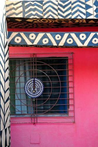 a building with a pink door with a fan in a window at Maison d'hôtes Chez Giuliana in Ouagadougou