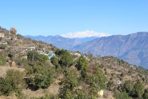 a town on a hill with mountains in the background at THE GROOVE GARDEN DHANOLTi in Dhanaulti