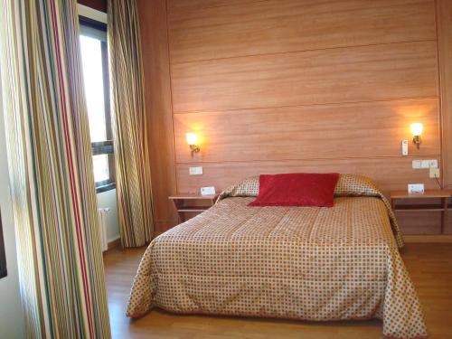 a bedroom with a bed with a red pillow on it at Hotel Castilla in Albacete