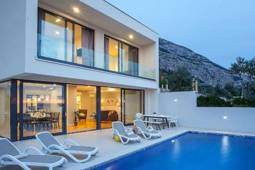a house with a swimming pool with lounge chairs next to it at Villa Sima in Makarska