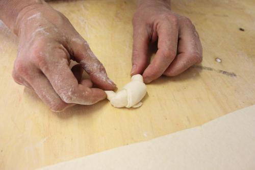 a person cutting a piece of food on a cutting board at Hotel Loretta & Dependance in Cervia