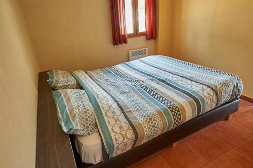 a bed with a quilt on it in a room at Le Lac Bleu in Lacapelle-Marival