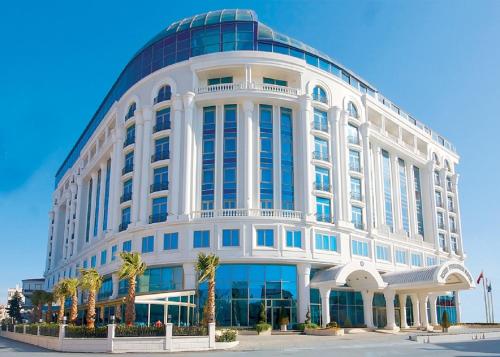 a large white building with palm trees in front of it at Eser Premium Hotel & Spa in Büyükçekmece