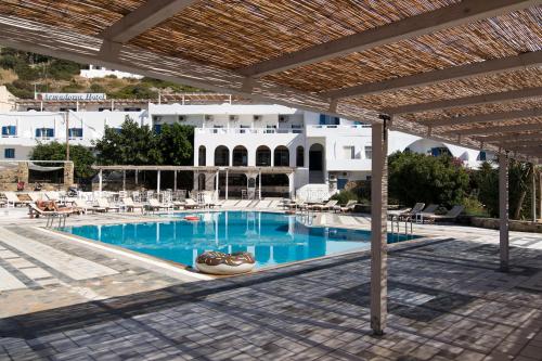 a swimming pool with chairs and a building in the background at Armadoros Hotel / Ios Backpackers in Ios Chora