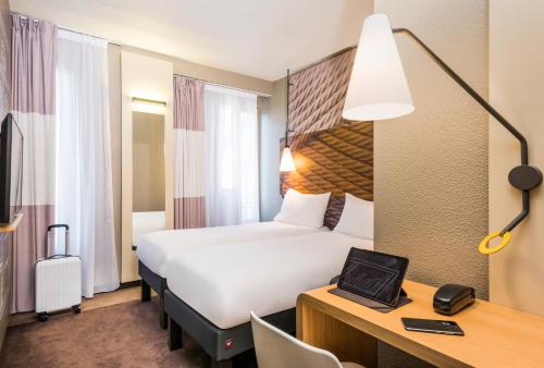 ein Hotelzimmer mit einem großen Bett und einem Schreibtisch in der Unterkunft ibis Clichy Centre Mairie in Clichy