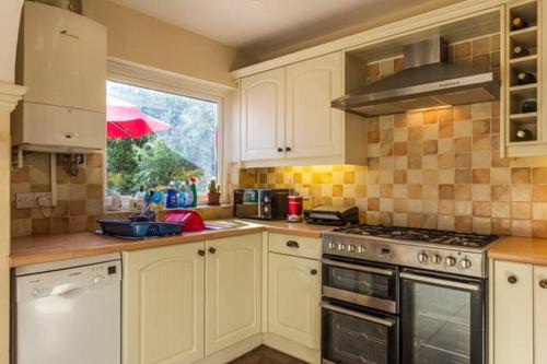 uma cozinha com armários brancos e uma janela com um guarda-chuva em Endearing Edwardian House in Quaint Deal, Kent em Deal