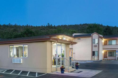 a building in a parking lot with a mountain in the background at Travelodge by Wyndham Williams Grand Canyon in Williams