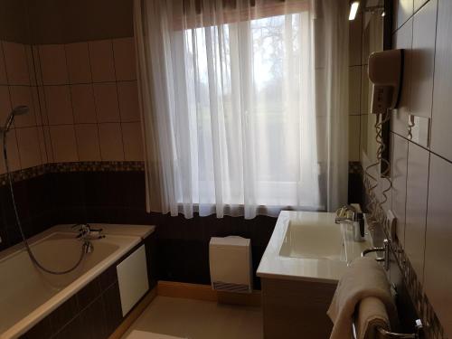 a bathroom with a sink and a tub and a window at LOGIS - Château de la Motte - Hôtel & Restaurant in Liessies