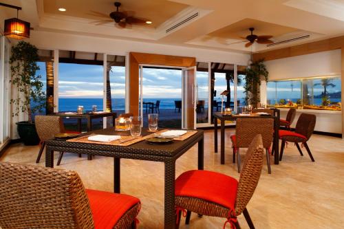 a dining room with tables and chairs with a view of the ocean at Dusit Thani Laguna Phuket in Bang Tao Beach