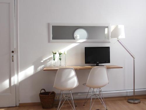 Habitación con 2 sillas blancas y escritorio con TV. en 7 Moons Bed & Breakfast en Valencia
